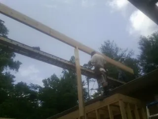 Carpenter setting a ridge beam over a new addition frame — Ice Dam Removal by Roofing Brothers in Spring Hill
