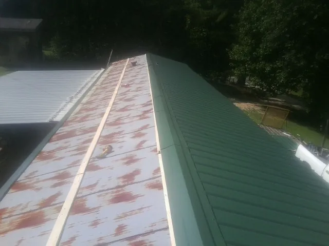 Old rusted panels beside newly installed green metal roofing — Wind Damage Roof Repair by Roofing Brothers in Spring Hill