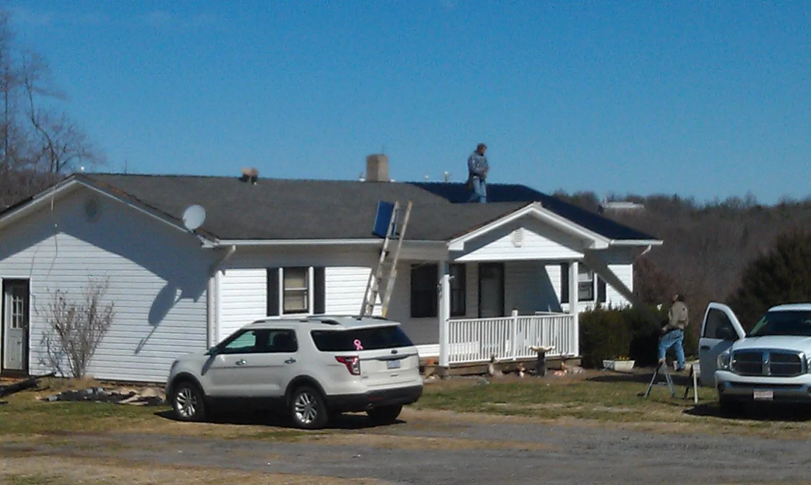 Roofers stripping shingles from a white ranch house roof in Spring Hill